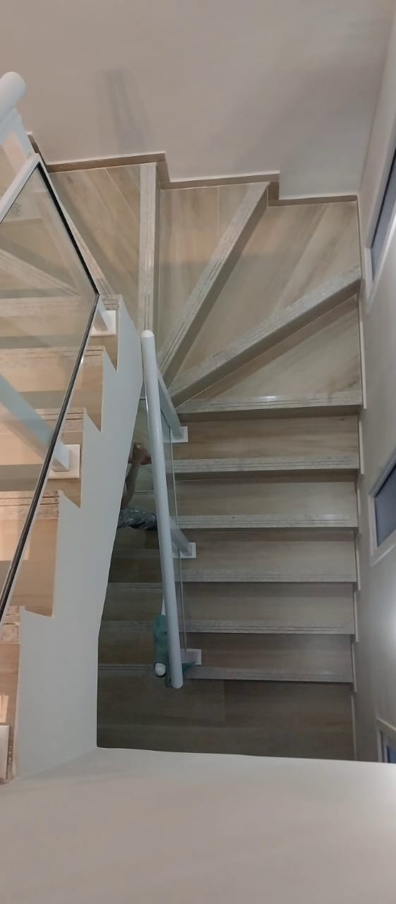 Escada interna em porcelanato claro com corrimão de vidro
